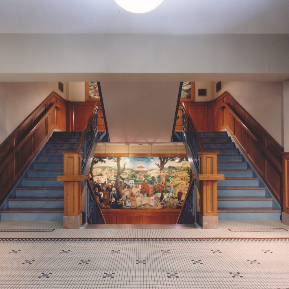 Two stairwells on each side with staircase in middle with wall mural inside Boone County Courthouse