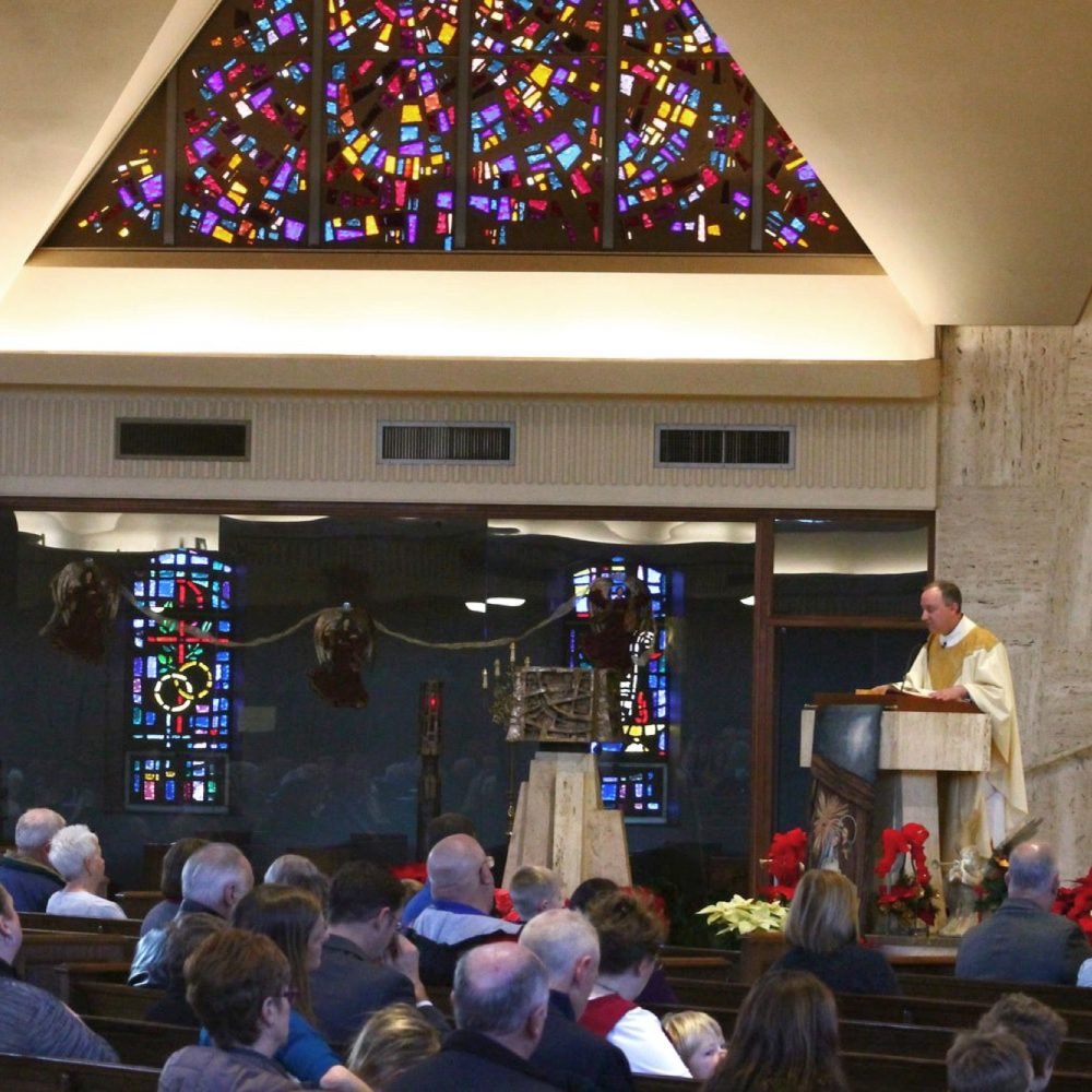 Inside of Cathedral of St. Joseph church with people sitting in pews and religious man at altar
